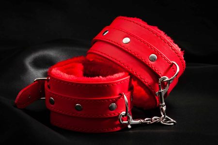 red bondage handcuffs on black background