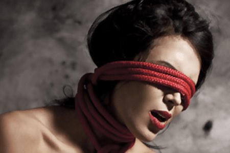 submissive woman with red bondage rope over her eyes
